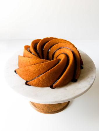 A chocolate-glazed Brazilian bolo de cenoura sits on a cake stand