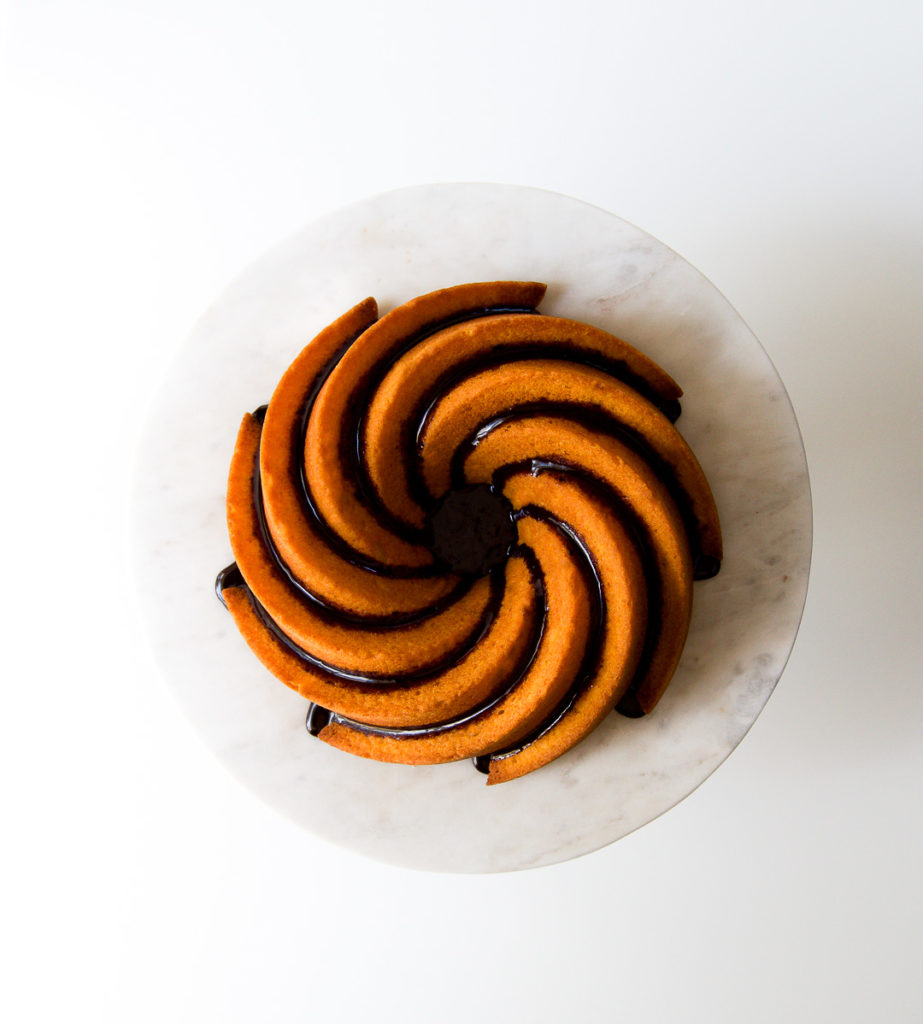 A Brazilian Carrot Cake drizzled with chocolate sauce on a white plate