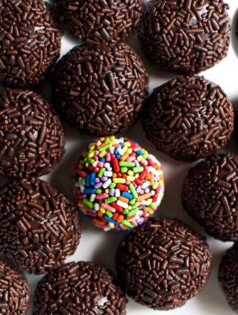 A rainbow fudge balls sits in the middle of a plate of chocolate Brazilian truffles