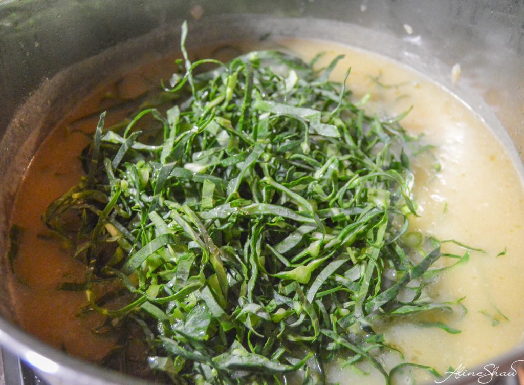 Finely cut collard greens on top of potato mixture in a pot
