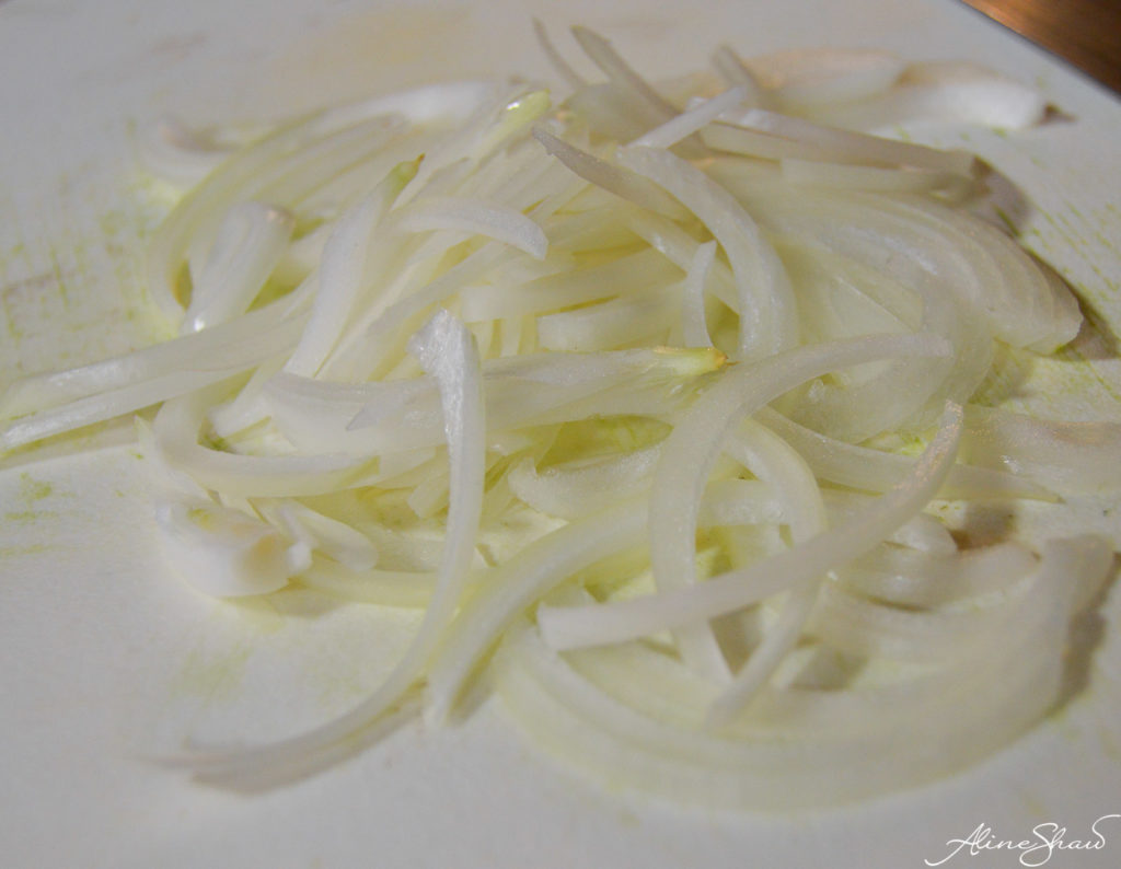 thinly sliced white onion on a cutting board