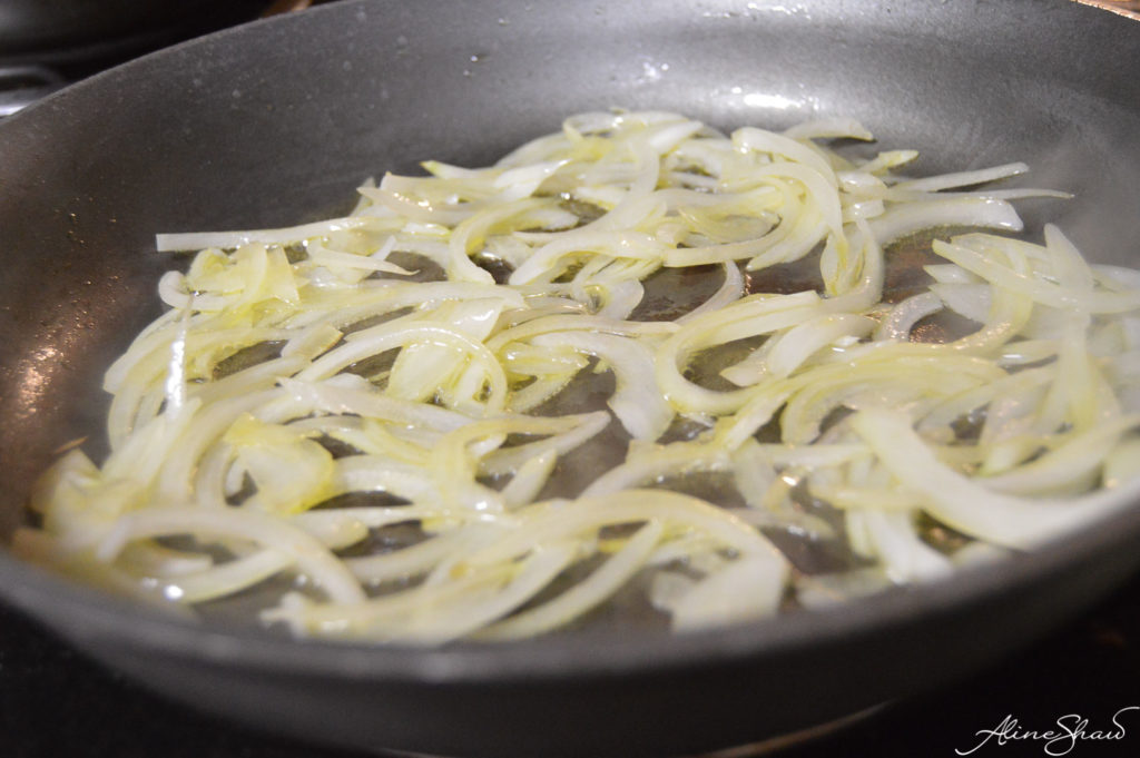sliced onions in a skillet cooking