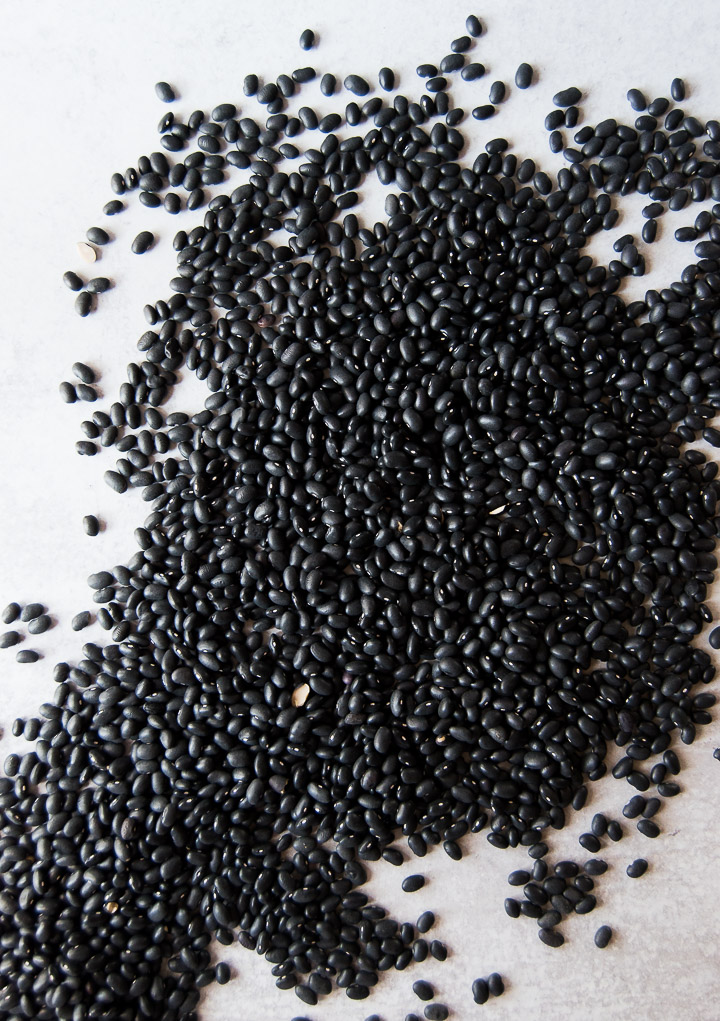 Lots of black beans scattered on a white background