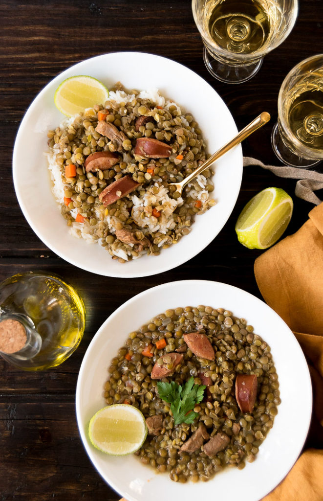 two bowls of lentil stew with pork and sausage on a wooden surface