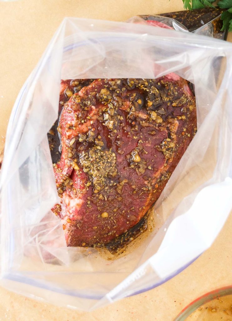 Steaks sit in marinade in a plastic bag