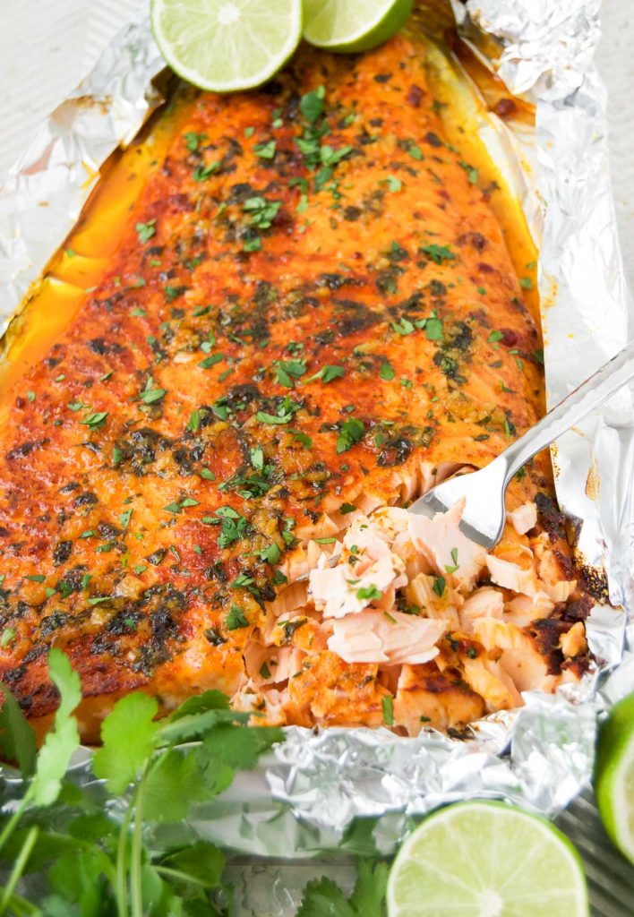 Baked Lime Salmon on a baking sheet with cilantro and lime halves