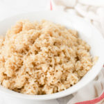 a white bowl holds a serving of fluffy brown rice