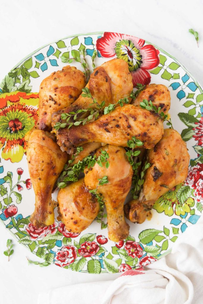 Baked Chicken Legs recipe on a colorful plate served with fresh thyme sprigs 