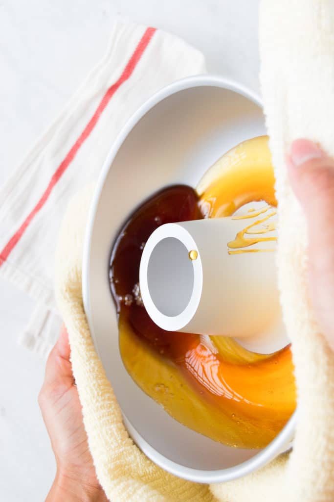 A woman swirls hot caramel around the bottom of a bundt pan