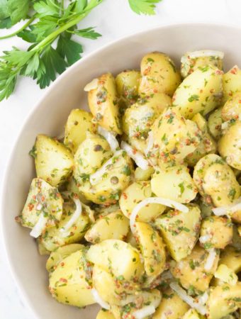 Vegan potato salad in a bowl next to fresh parsley