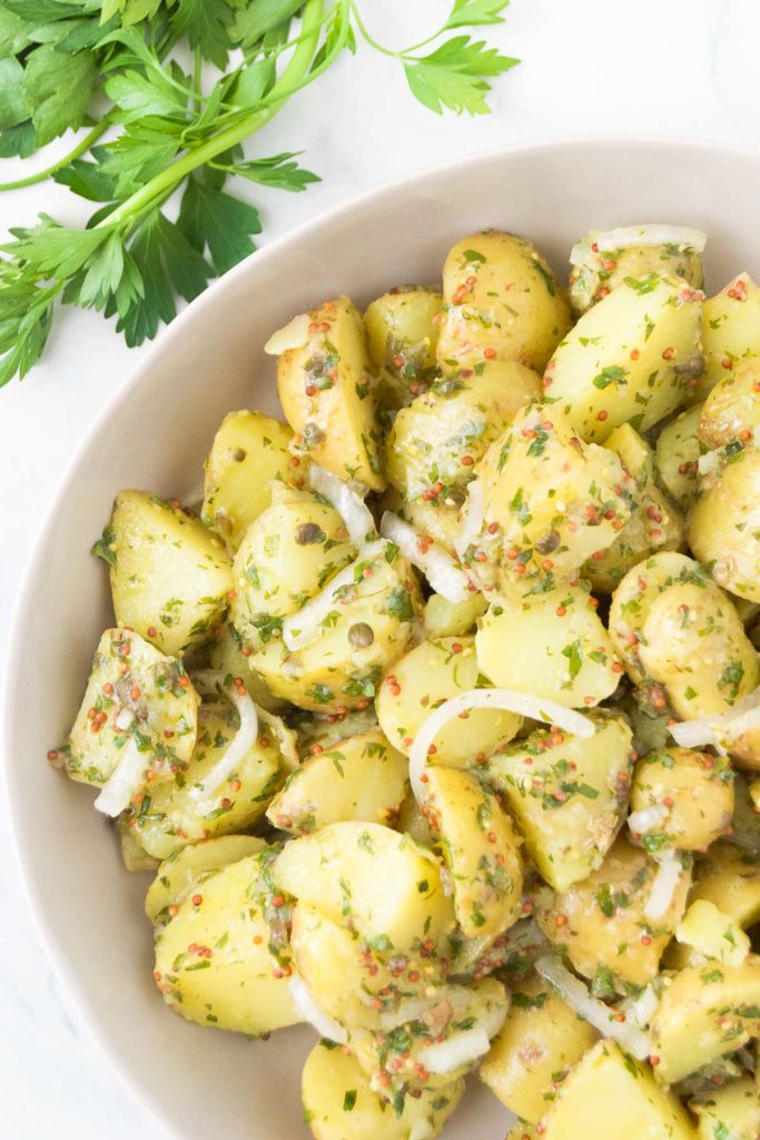 Vegan potato salad in a bowl next to fresh parsley