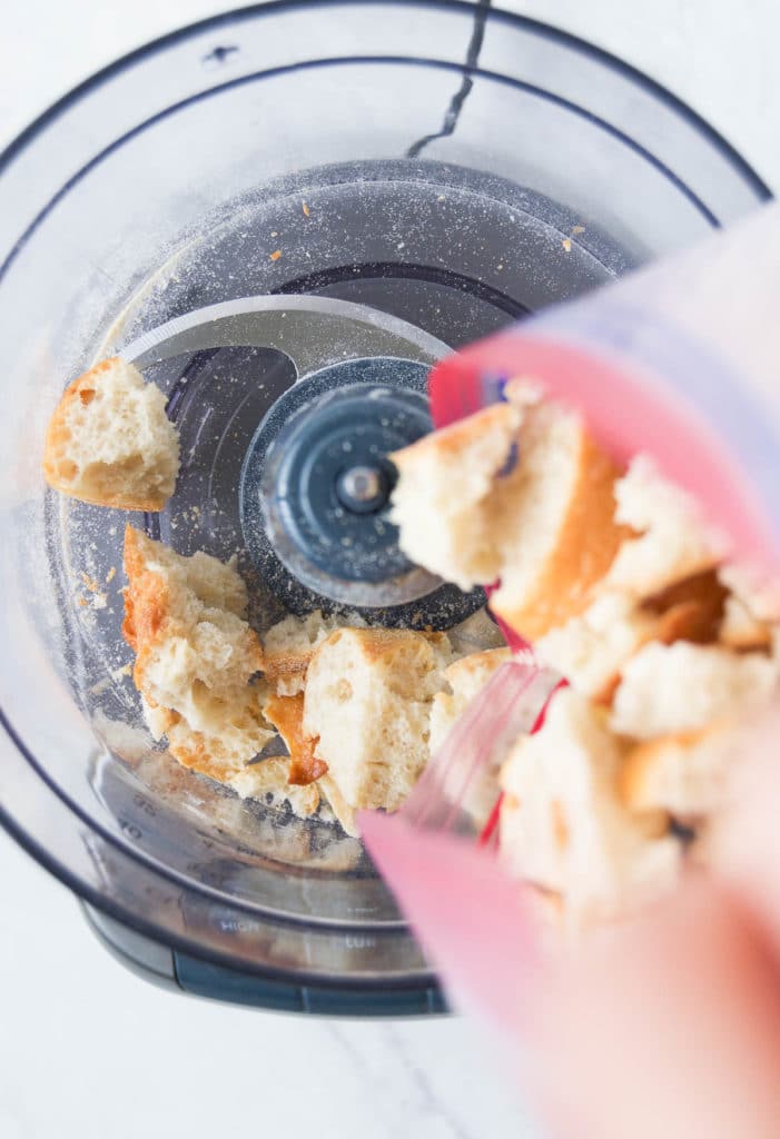 Bread chunks are dropped into a food processor from a plastic bag