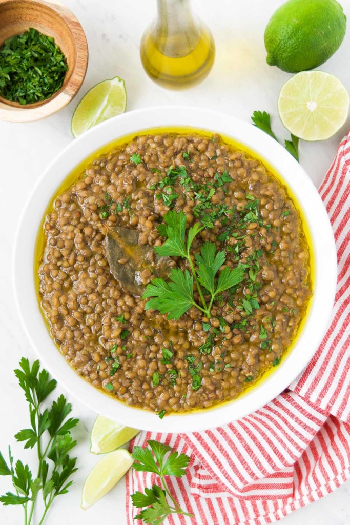 A bowl of green lentils in a bowl with parsley and a bay leaf