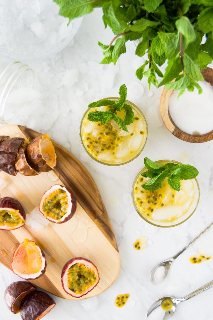 Two brazilian passion fruit cocktails with passion fruits, sugar and spoons