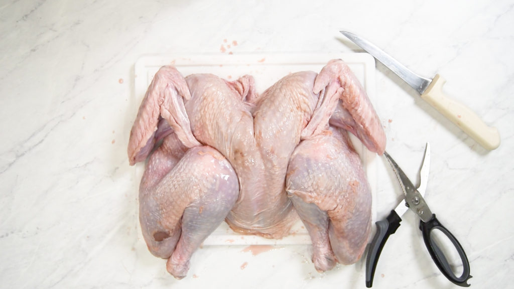 A spatchcock turkey on a plastic cutting board