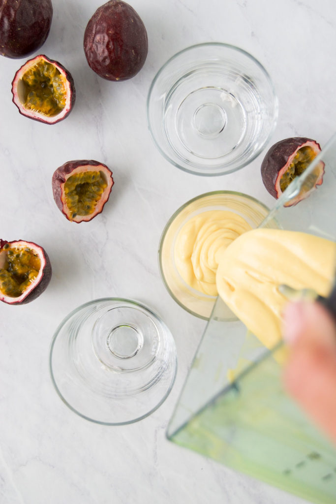 Mousse is poured into a glass next to halved purple passion fruits