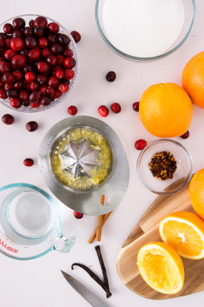 Cranberries, orange juice and other ingredients on a pink marble backdrop