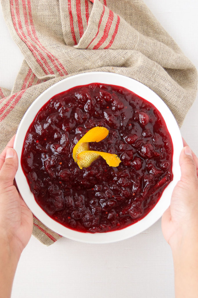 A woman holds a bowl of Spicy Cranberry Sauce