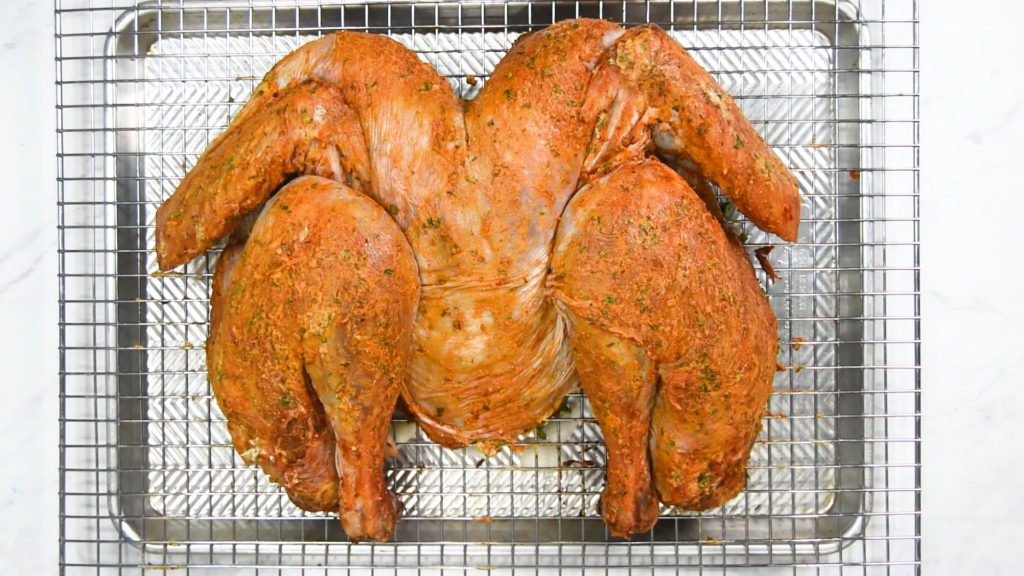 A spatchcock turkey before baking with compound butter