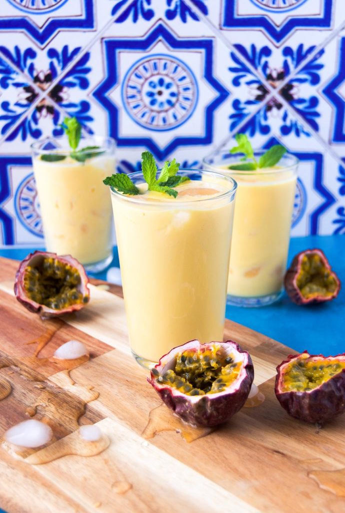 Three passion fruit drinks on wood with mint garnishes