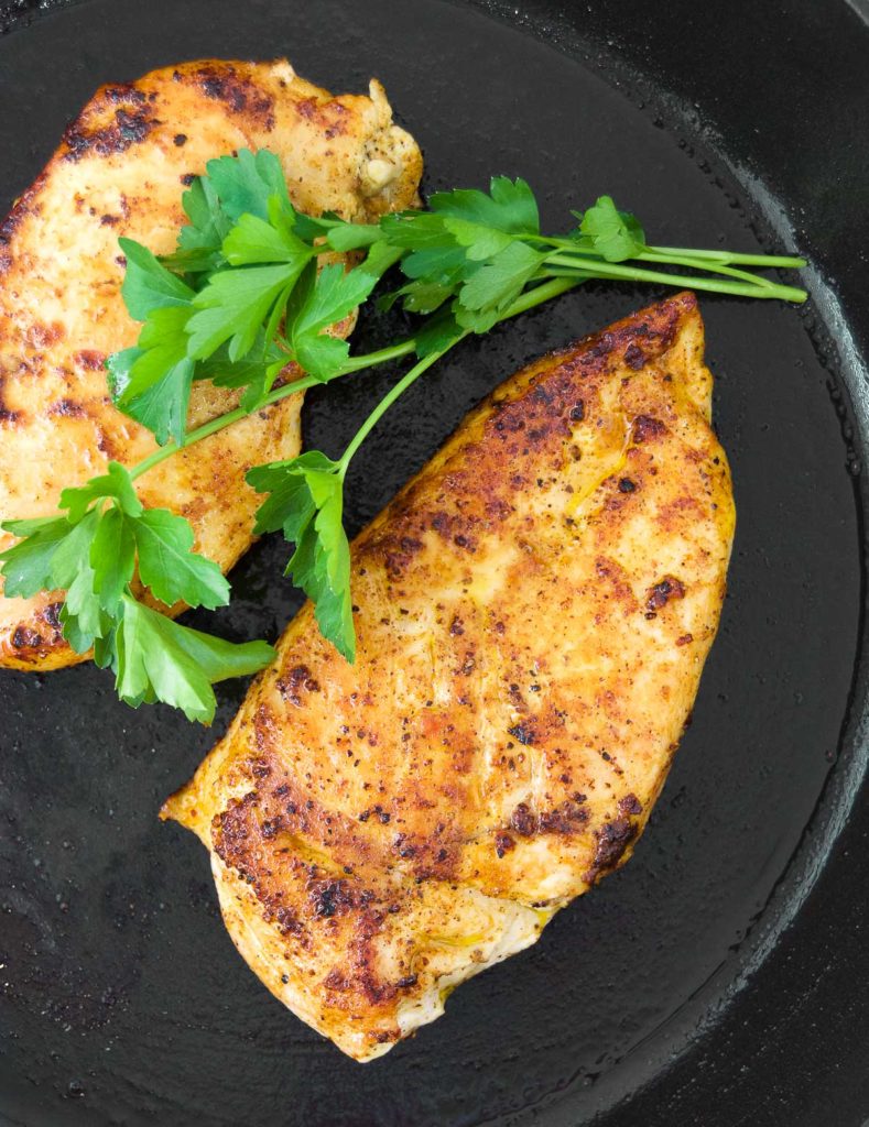 Close up of two chicken breasts in a cast iron skillet