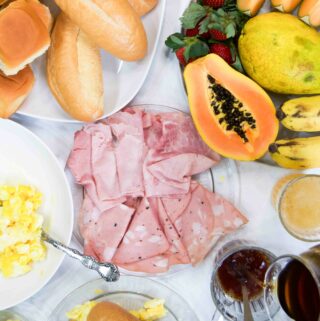 A Brazilian breakfast spread on a table with fresh fruit, cold cuts, coffee and more