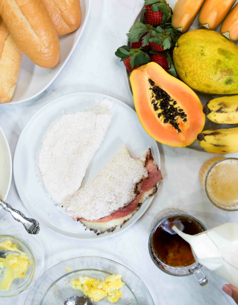 A Brazilian breakfast table with tapioca, coffee, eggs, fresh fruit, bread and more