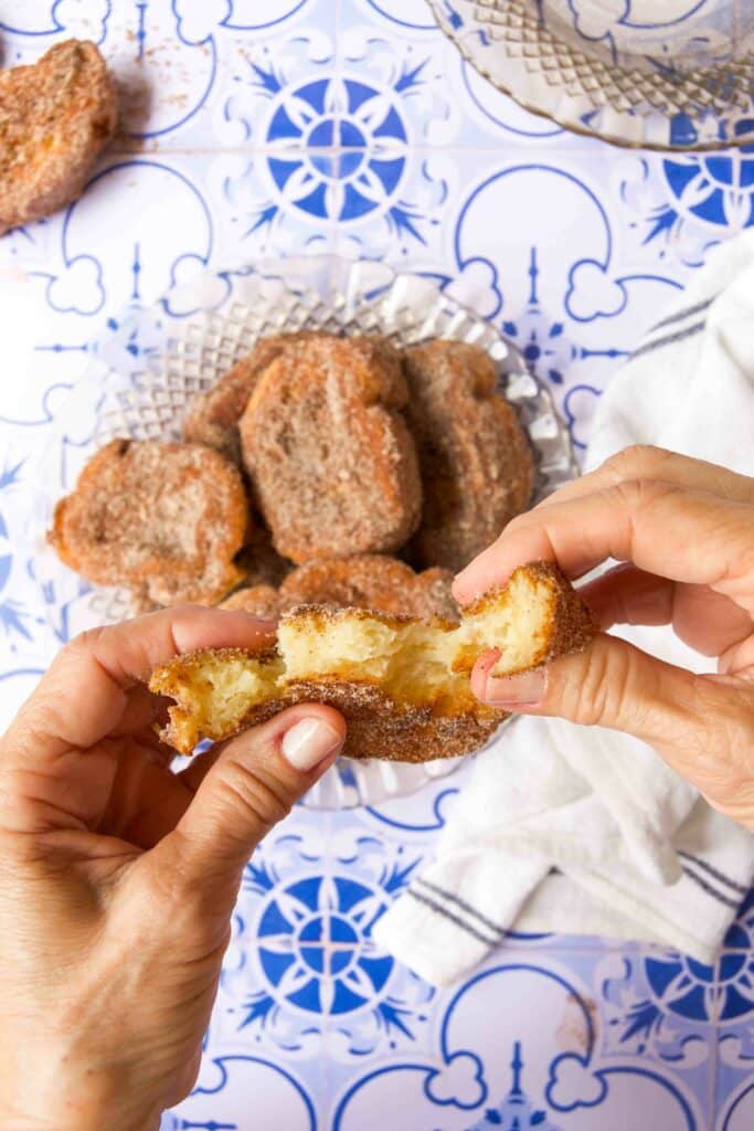A woman's hands pull apart a piece of cinnamon-sugar coated condensed milk French toast