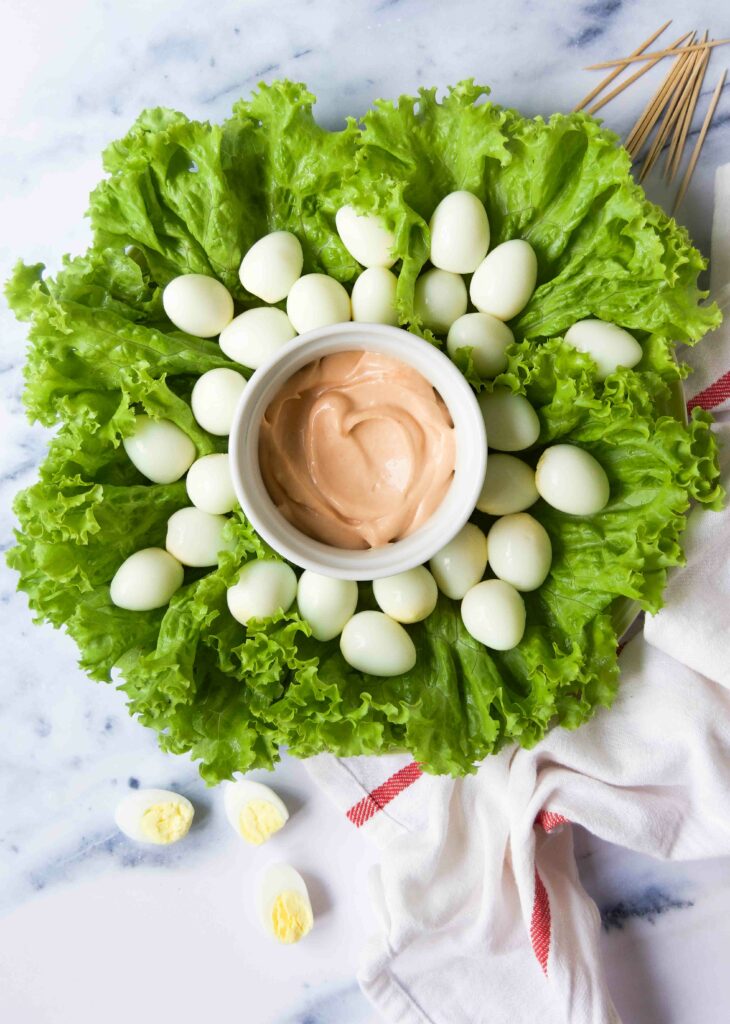 Boiled quail eggs on lettuce with a bowl of pink dipping sauce