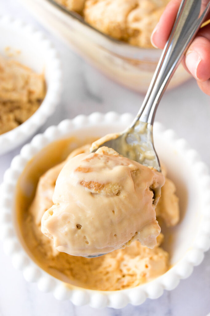 a spoon lifts a bite of dulce de leche ice cream out of a bowl 