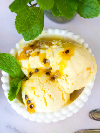 overhead close up of a bowl of passionfruit ice cream garnished with mint leaves and passion fruit puree