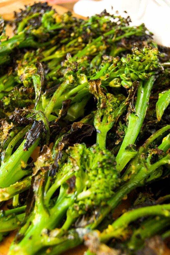 close up of grilled broccolini on a wooden board