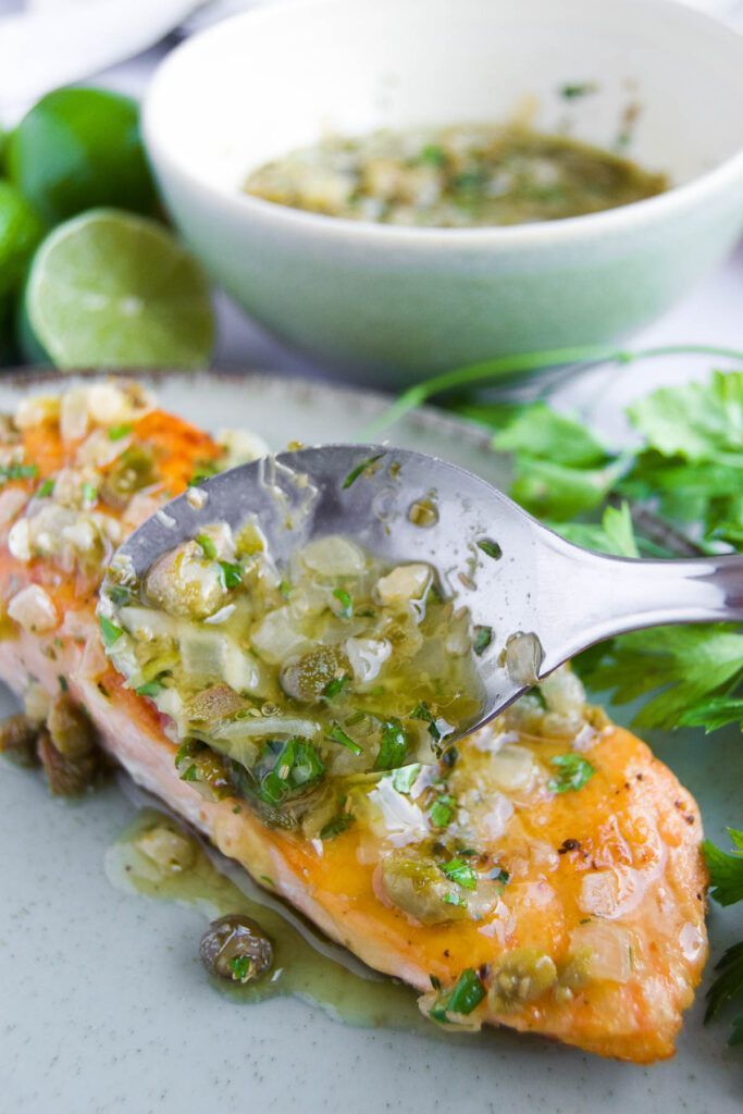 caper sauce is spooned onto a filet of salmon