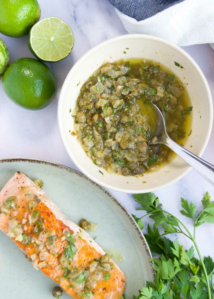 a bowl of caper sauce for fish next to a plate of salmon