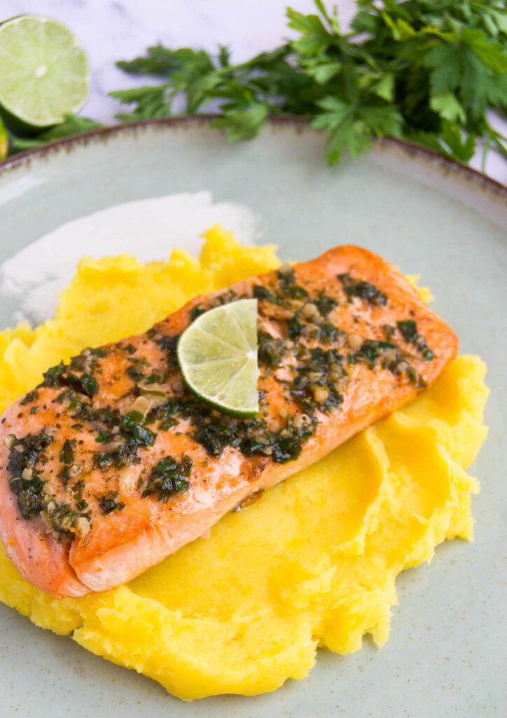 seared salmon with a butter sauce on top of puree de batata baroa on a plate